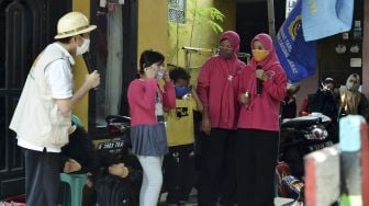 Pendongeng Adi Pamungkas (kiri) memberikan petunjuk bagaimana cara memakai masker yang benar kepada dua orang anak saat mendongeng di hadapan anak-anak warga Cakung Barat, Jakarta Timur, Sabtu (14/11/2020). [ANTARA FOTO/Suwandy]