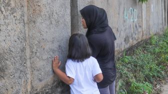 Warga menonton momen pernikahan Komedian Sule dengan Nathalie Holscher dari sela - sela dinding di Jatisampurna, Bekasi, Jawa Barat, Minggu (15/11). [Suara.com/Alfian Winanto] 