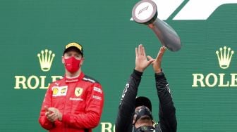 Pebalap Mercedes Lewis Hamilton melempar trofi ke udara di podium usai memenangi balapan F1 Grand Prix Turki di Istanbul, Minggu (15/11/2020). MURAD SEZER / POOL / AFP
