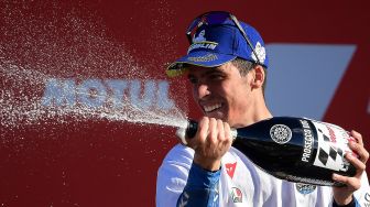 Pebalap Suzuki Ecstar, Joan Mir, merayakan kemenangan setelah memenangkan kejuaraan dunia MotoGP setelah Grand Prix Valencia di sirkuit Ricardo Tormo, Valencia, Spanyol, Minggu (15/1).  [LLUIS GENE / AFP]