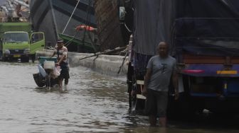 Pedagang keliling melintasi banjir rob yang menggenangi kawasan Sunda Kelapa, Jakarta, Selasa (17/11/2020). [Suara.com/Angga Budhiyanto]