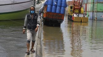 Seorang warga melintasi banjir rob yang menggenangi kawasan Sunda Kelapa, Jakarta, Selasa (17/11/2020). [Suara.com/Angga Budhiyanto]