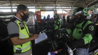 Petugas mencatat hasil uji emisi kendaraan bermotor kepada pengemudi ojek online di Kantor Dinas Lingkungan Hidup DKI Jakarta, Kramat Jati, Jakarta, Kamis (19/11/2020). [Suara.com/Angga Budhiyanto]