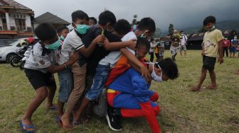 Seorang relawan menggunakan kostum super hero saat bermain bersama anak-anak di Tempat Pengungsian Sementara Gunung Merapi, Klakah, Selo, Boyolali, Jawa Tengah, Sabtu (21/11/2020).  [ANTARA FOTO/Aloysius Jarot Nugroho]
