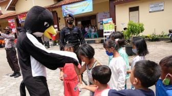 Personel detasemen Gegana berpakaian maskot walet hitam menghibur anak-anak pengungsi saat penyaluran bantuan bagi pengungsi di tempat pengungsian Merapi Desa Deyangan, Magelang, Jateng, Sabtu (21/11/2020).  [ANTARA FOTO/Anis Efizudin]
