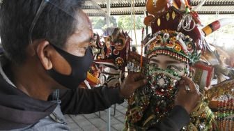 Orang tua membantu anaknya mengenakan masker sebelum mengikuti virtual World Kids Carnival (WKC) 2020 di Jember, Jawa Timur, Minggu (22/11/2020). [ANTARA FOTO/Seno]