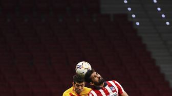 Penyerang Atletico Madrid Diego Costa (kanan) menyundul bola dengan bek Barcelona Sergi Roberto selama pertandingan sepak bola Liga Spanyol antara Club Atletico de Madrid melawan FC Barcelona di stadion Wanda Metropolitano, Madrid, pada (21/11/2020). [GABRIEL BOUYS / AFP]