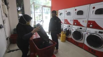 Pekerja menerima orderdari pelanggan di Jourdan Laundry Expert, Ampera Raya, Jakarta, Kamis (26/11/2020). [Suara.com/Angga Budhiyanto]