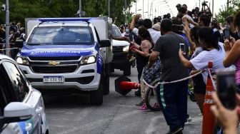 Sebuah mobil polisi ilmiah yang membawa jenazah bintang sepak bola Argentina Diego Maradona meninggalkan komunitas yang terjaga keamanannya di mana dia meninggal, di Benavidez, provinsi Buenos Aires, Argentina, Rabu (25/11). [RONALDO SCHEMIDT / AFP]