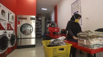 Pekerja melakukan pengemasan baju pelanggan sebagai tahapan akhir di Jourdan Laundry Expert, Ampera Raya, Jakarta, Kamis (26/11/2020). [Suara.com/Angga Budhiyanto]