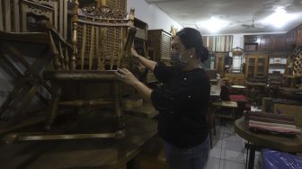 Pemilik usaha mebel kayu merapikan produk mebel yang dipajang di salah satu workshop furniture di kawasan Kemang, Jakarta, Kamis (26/11/2020). [Suara.com/Angga Budhiyanto]