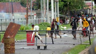 Massa berjalan melintasi asap yang mengepul saat unjuk rasa di Kota Sorong, Papua Barat, Jumat (27/11/2020). ANTARA FOTO/Olha Mulalinda