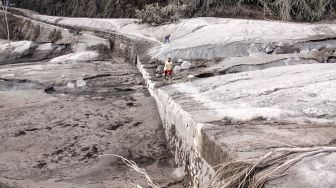 Warga berjalan di samping jalur lahar panas Gunung Semeru di kawasan Pronojiwo, Lumajang, Jawa Timur, Rabu (2/12/2020). [ANTARA FOTO/Umarul Faruq]
