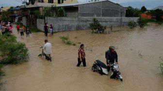 Warga melintasi banjir yang merendam pemukiman penduduk di Kecamatan Sunggal, Deli Serdang, Sumatera Utara, Jumat (4/12/2020).  [ANTARA FOTO/Irsan Mulyadi]