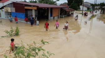 Warga melintasi banjir yang merendam pemukiman penduduk di Kecamatan Sunggal, Deli Serdang, Sumatera Utara, Jumat (4/12/2020).  [ANTARA FOTO/Irsan Mulyadi]