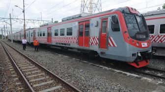 Petugas melintas didekat Kereta Rel Listrik (KRL) saat berada di Stasiun Klaten, Jawa Tengah, Jumat (4/12/2020). [ANTARA FOTO/Aloysius Jarot Nugroho]