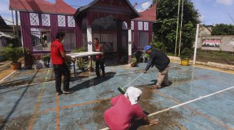 Petugas dibantu warga mempersiapkan Tempat Pemungutan Suara (TPS) dengan nuansa adat Padang di Kampung Benda Barat, Kelurahan Cipayung, Kota Depok, Jawa Barat, Selasa (8/12/2020). [Suara.com/Angga Budhiyanto]