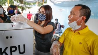 Pedangdut Ayu Ting Ting bersama sang ayah, Abdul Rozak memasukkan surat suaranya kedalam kotak suara saat melakukan pemilihan kepala daerah di TPS 06 Sukmajaya, Depok, Jawa Barat, Rabu (9/12). [Suara.com/Alfian Winanto]