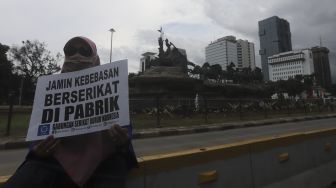 Seorang massa buruh membawa poster saat melakukan aksi unjuk rasa di kawasan Patung Kuda Arjuna Wiwaha, Jakarta, Kamis (10/12/2020). [Suara.com/Angga Budhiyanto]