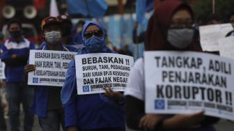 Sejumlah massa buruh membawa poster saat melakukan aksi unjuk rasa di kawasan Patung Kuda Arjuna Wiwaha, Jakarta, Kamis (10/12/2020). [Suara.com/Angga Budhiyanto]