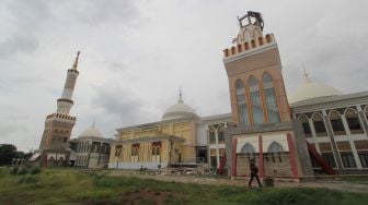 Warga melintas di sekitar menara Masjid Syech Abdul Manan Islamic Center yang roboh di Indramayu, Jawa Barat, Rabu (9/12/2020).   [ANTARA FOTO/Dedhez Anggara]
