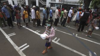 Seorang anak bergegas usai mengambil makanan gratis di Kotak Amal Makanan Gratis di pelataran Masjid Cut Meutia, Jakarta, Jumat (11//12/2020). [Suara.com/Angga Budhiyanto]