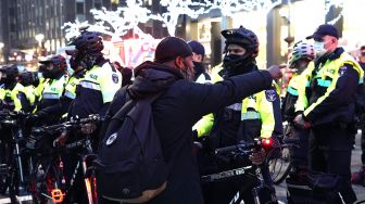 Seorang pengunjuk rasa berteriak pada petugas NYPD setelah sebuah mobil menabrak beberapa pengunjuk rasa Black Lives Matter pada 11 Desember 2020. [TIMOTHY A. CLARY / AFP]
