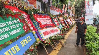 Warga melihat karangan bunga yang membanjiri halaman depan Polda Metro Jaya, Jakarta Selatan, (12/12). [Suara.com/Alfian Winanto]