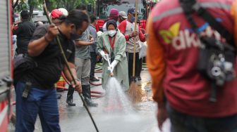 Wali Kota Surabaya Tri Rismaharini (tengah) membersihkan jalan saat kerja bakti pembersihan saluran air di Mulyosari, Surabaya, Jawa Timur, Sabtu (12/12/2020).  ANTARA FOTO/Didik Suhartono
