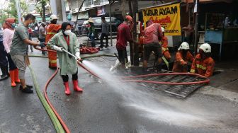 Wali Kota Surabaya Tri Rismaharini (tengah) membersihkan jalan saat kerja bakti pembersihan saluran air di Mulyosari, Surabaya, Jawa Timur, Sabtu (12/12/2020).  ANTARA FOTO/Didik Suhartono
