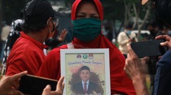 Keluarga memegang foto ketua KPU Kota Tangerang Selatan almarhum Bambang Dwitoro saat akan dimakamkan di TPU khusus COVID-19 Jombang, Tangerang Selatan, Banten, Sabtu (12/12/2020). [ANTARA FOTO/Muhammad Iqbal]
