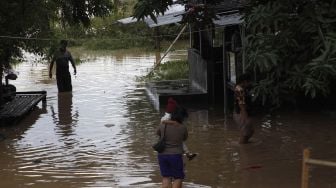 Warga berjalan melintasi banjir yang menggenangi permukiman di Kampung Sewu, Jebres, Solo, Jawa Tengah, Senin (14/12/2020). ANTARA FOTO/Maulana Surya