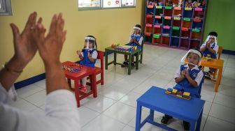 Seorang guru bersama murid melakukan simulasi pembukaan dan pembelajaran tatap muka Taman Kanak-kanak (TK) dengan protokol kesehatan di TK Negeri Pembina Cimahi, Jawa Barat, Senin (14/12/2020).  [ANTARA FOTO/Raisan Al Farisi]