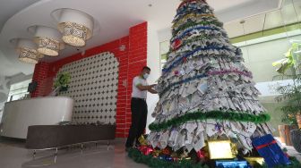 Pekerja merangkai kertas koran bekas saat membuat pohon Natal di Hotel Zest, Surabaya, Jawa Timur, Kamis (17/12/2020). [ANTARA FOTO/Didik Suhartono]