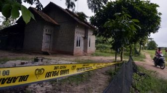 Warga melintasi rumah terduga teroris Taufik Bulaga alias Upik Lawanga di Desa Sribawono, Lampung Tengah, Lampung (19/12/2020). [ANTARA FOTO/Ardiansyah]