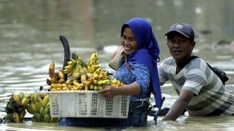 Pedagang menyelamatkan barang dagangannya dari banjir di Pasar Gurem Pamekasan, Jawa Timur, Sabtu (19/12/2020). [ANTARA FOTO/Saiful Bahri]