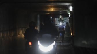 Seorang warga berjalan melintasi jalur alternatif di bawah kolong jalan tol Jagorawi di kawasan Terminal Kampung Rambutan, Jakarta, Rabu (23/12/2020). [Suara.com/Angga Budhiyanto]