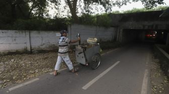 Seorang pedagang berjalan memasuki jalur alternatif di bawah kolong jalan tol Jagorawi di kawasan Terminal Kampung Rambutan, Jakarta, Rabu (23/12/2020). [Suara.com/Angga Budhiyanto]