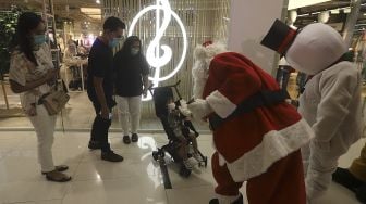 Petugas mengenakan kostum Santa Claus saat menghibur pengunjung di Senayan City Mall, Jakarta, Jumat (25/12/2020). [Suara.com/Angga Budhiyanto]