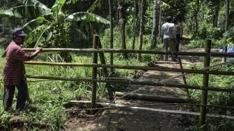 Warga menorobos pagar bambu menuju ke tempat pemakaman di Dusun Landeuh, Desa Sindangherang, Kabupaten Ciamis, Jawa Barat, Kamis (24/12/2020).  ANTARA FOTO/Adeng Bustomi
