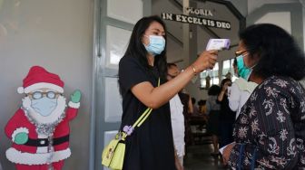 Petugas mengecek suhu tubuh umat Katolik saat misa Natal 2020 di Gereja St. Thomas, Seyegan, Sleman, D.I Yogyakarta, Kamis (24/12/2020). [ANTARA FOTO]
