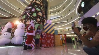 Pengunjung berfoto bersama petugas yang mengenakan kostum Santa Claus di Senayan City Mall, Jakarta, Jumat (25/12/2020). [Suara.com/Angga Budhiyanto]