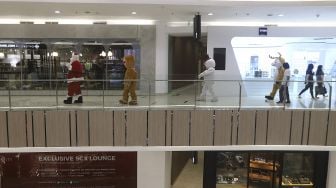 Petugas mengenakan kostum Santa Claus saat menghibur pengunjung di Senayan City Mall, Jakarta, Jumat (25/12/2020). [Suara.com/Angga Budhiyanto]