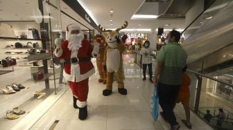 Petugas mengenakan kostum Santa Claus saat menghibur pengunjung di Senayan City Mall, Jakarta, Jumat (25/12/2020). [Suara.com/Angga Budhiyanto]