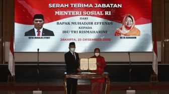 Menteri Koordinator Bidang Pembangunan Manusia dan Kebudayaan yang juga pejabat lama Menteri Sosial Ad Interim Muhajir Effendi (kiri) bersama Menteri Sosial Tri Rismaharini (kanan) menunjukan berkas berita acara serah terima jabatan Menteri Sosial di Kantor Kementerian Sosial, Jakarta, Rabu (23/12/2020). Tri Rismaharini resmi diangkat Presiden Joko Widodo menjadi Menteri Sosial menggantikan Juliari Batubara yang tersandung kasus korupsi dana Bantuan Sosial (Bansos). [Suara.com/Angga Budhiyanto]
