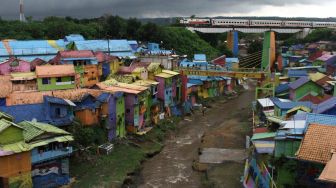 Wisatawan memanfaatkan libur tahun baru dengan berekreasi di Kampung Warna-Warni Jodipan, Malang, Jawa Timur, Jumat (1/1/2021). ANTARA FOTO/Ari Bowo Sucipto
