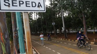 Warga berolahraga di kawasan Banjir Kanal Timur (BKT), Jakarta Timur, Jumat (1/1/2020). [Suara.com/Alfian Winanto]