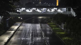 Warga berjalan saat diberlakukannya Car Free Night (malam bebas kendaraan) dan Crowd Free Night (malam bebas keramaian) pada malam pergantian tahun di Jalan Sudirman, Jakarta, Kamis (31/12/2020). [Suara.com/Angga Budhiyanto]