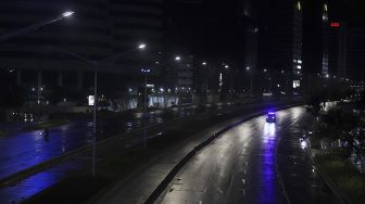 Petugas kepolisian melaksanakan patroli  saat diberlakukannya Car Free Night (malam bebas kendaraan) dan Crowd Free Night (malam bebas keramaian) pada malam pergantian tahun di Jalan Sudirman, Jakarta, Kamis (31/12/2020). [Suara.com/Angga Budhiyanto]