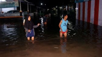 Sejumlah warga melintasi genangan banjir di Desa Tembok Lor, Kabupaten Tegal, Jawa Tengah, Jumat (1/1/2021) malam.  ANTARA FOTO/Oky Lukmansyah